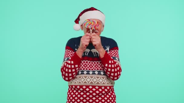할아버지는 크리스마스 스웨터를 입고 사탕 줄무늬 롤리팝을 들고 뒤에 숨어서 — 비디오