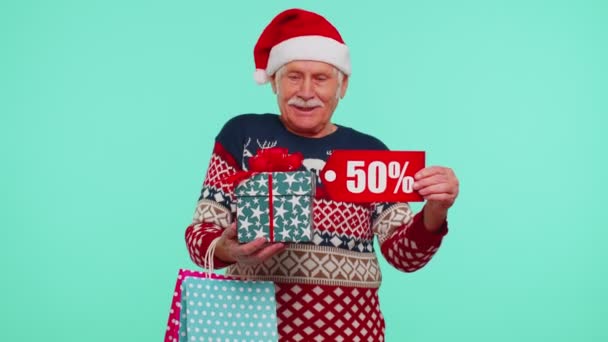 Oudere man in kersttrui met geschenkdoos en 50 Procent korting inscripties banner tekst — Stockvideo