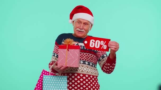 Dědeček ve vánočním svetru ukazuje dárkové krabice a 60 Procento sleva nápisy banner text — Stock video