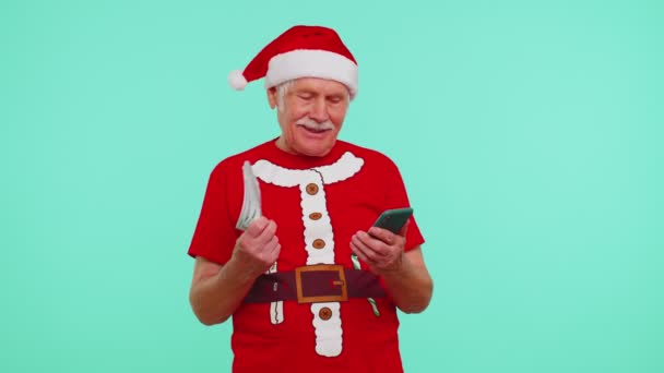 Kakek Natal mencari smartphone dengan tulus bersukacita memenangkan kesuksesan dan menerima uang secara online — Stok Video