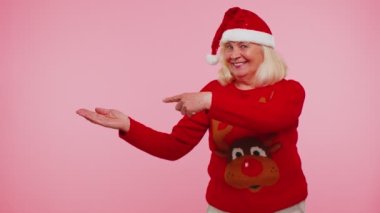 Noel Baba süveteri giymiş büyükannem başparmağını kaldırıyor ve boş bir yeri işaret ediyor.