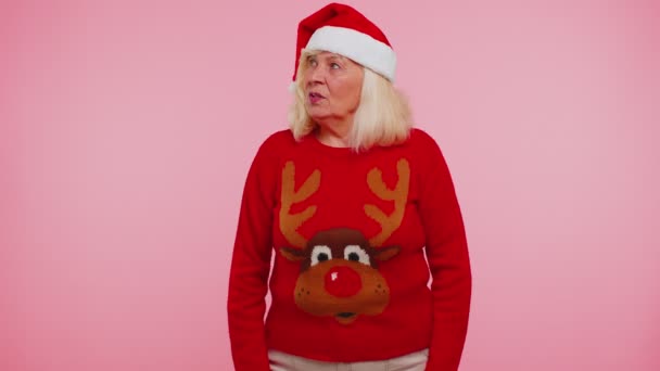 산타 크리스마스 스웨터를 입은 할머니가 놀라운 행복을 표현 한 선물 상자를 받고 있습니다 — 비디오