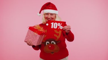 Noel süveteri giyen büyük anne hediye kutusu ve% 10 indirimli yazı gösteriyor.