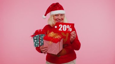 Noel süveteri giyen büyükannem hediye kutusu ve yüzde 20 indirimli yazı gösteriyor.