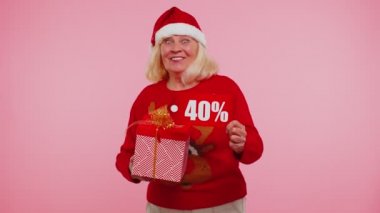 Noel süveteri giyen büyükannem hediye kutusu ve% 40 indirimli yazı gösteriyor.