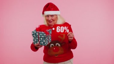 Noel süveteri giyen büyükannem hediye kutusu ve% 60 indirimli yazı gösteriyor.