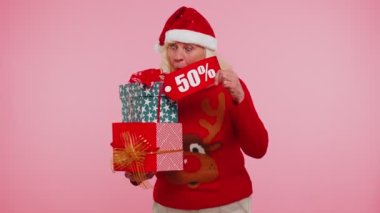 Noel süveteri giyen yaşlı bir kadın hediye kutusu ve% 50 indirimli yazı gösteriyor.