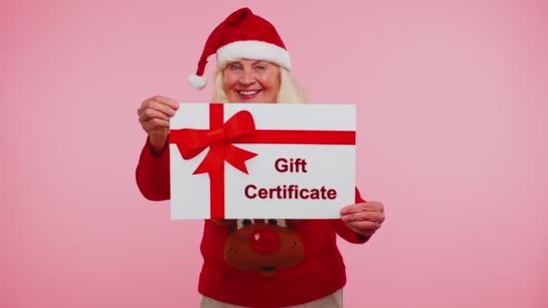 Femeia bunică în vârstă în pulover de Anul Nou care prezintă certificatul de cadou de card voucher câștigător cupon — Videoclip de stoc