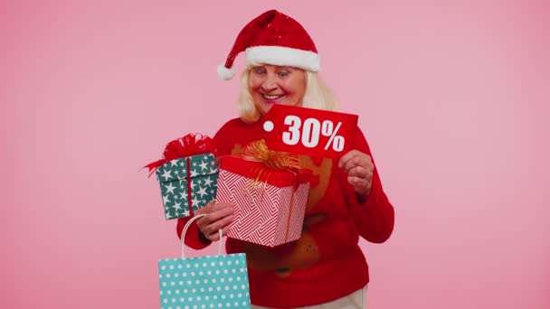 Senior nő karácsonyi pulóver mutatja ajándékdoboz és 30 százalékos kedvezmény feliratok banner szöveg — Stock videók