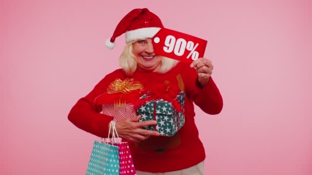 Senior γυναίκα σε χριστουγεννιάτικο πουλόβερ δείχνει κουτί δώρου και 90 τοις εκατό έκπτωση επιγραφές banner κείμενο — Αρχείο Βίντεο