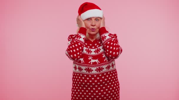 Noel kıyafetleri içinde kıdemli büyükanne kadın kulakları örtüyor, hayır işareti yapıyor, tavsiyelerden kaçınıyor, görmezden geliyor. — Stok video