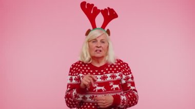 Kızgın yaşlı kadın Noel geyiği boynuzları içinde öfkeli bir ifadeyle el kaldırıyor.