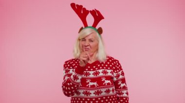Memnun olmayan yaşlı Noel kadını, hoşnutsuzlukla el kol hareketi yapıyor, başarısızlıktan dolayı azarlıyor.