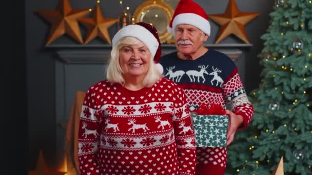 Abuelo cubriendo los ojos de la abuela de edad con sorpresa regalo de Navidad caja de regalo en la habitación de casa — Vídeo de stock