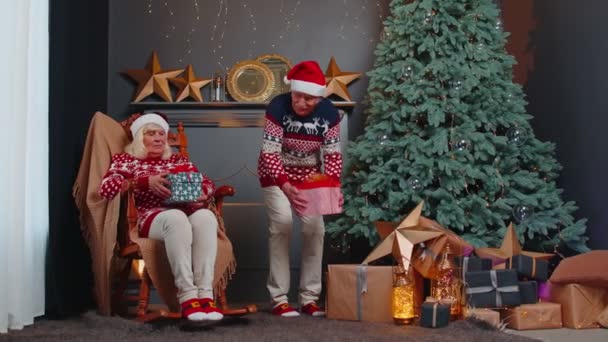 Μεγαλύτερο οικογενειακό ζευγάρι γιαγιά παρουσιάζοντας κουτιά δώρων Χριστουγέννων ο ένας στον άλλο στο σπίτι — Αρχείο Βίντεο