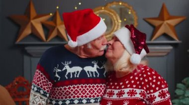 Yaşlı çift büyükanne öpüşüyor, kameraya bakıyor, Noel 'i kutluyor.