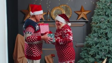 Romantik son sınıf çifti Noel ağacını süslemek için birbirlerine hediye kutuları sunuyorlar.