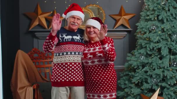 Gelukkig senior kerst familie glimlachend vriendelijk op camera en zwaaiende handen gebaren hallo of vaarwel — Stockvideo