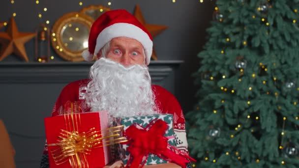 Kakek senior memparodikan Santa Claus mempersembahkan kotak hadiah Natal, perayaan liburan di rumah — Stok Video