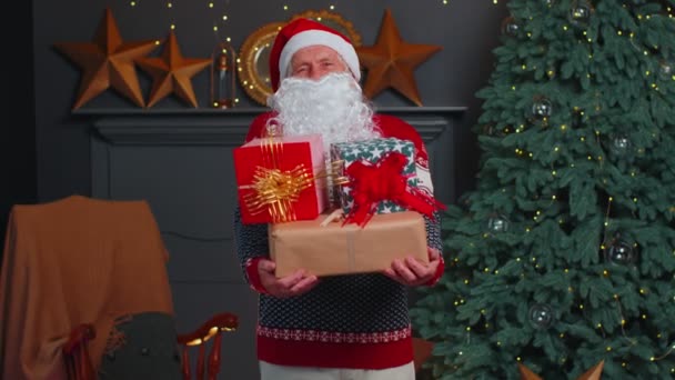 Senior grandfather parodies Santa Claus presenting Christmas gift box, holidays celebration at home — Stock Video