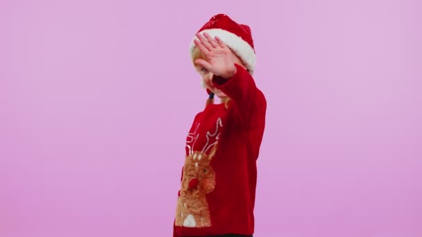Menina em ondas de camisola de Natal palma da mão em Olá gesto recebe alguém para comemorar o Ano Novo — Vídeo de Stock