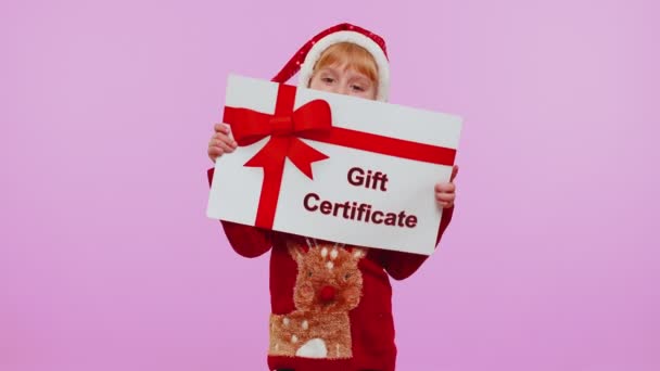 Funny girl wears Navidad Santa sombrero y sombrero de presentación de tarjeta de regalo cupón ganador del cupón — Vídeo de stock