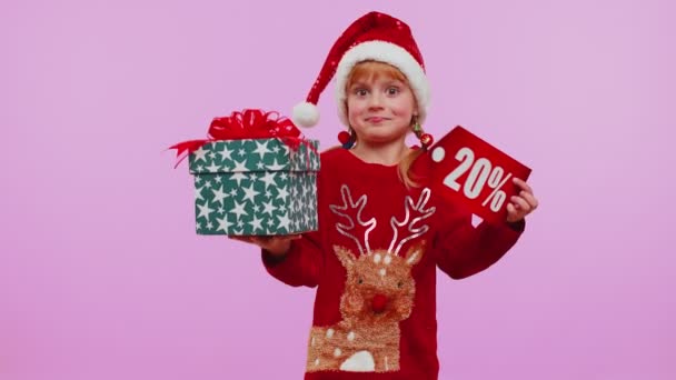 Niña en sombrero de Navidad mostrando caja de regalo y 20 por ciento de descuento inscripciones banner texto nota — Vídeo de stock