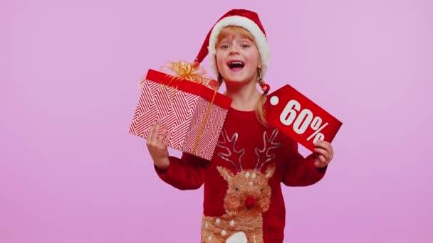 Niña en sombrero de Navidad mostrando cajas de regalo y 60 por ciento de descuento inscripciones banner texto nota — Vídeo de stock