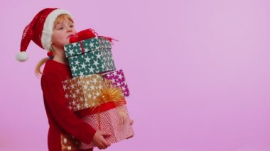 Noel kazaklı kız, Noel Baba şapkalı, gülümseyen, elinde bir sürü hediye kutusu olan yeni yıl hediyesi alışverişi yapan.