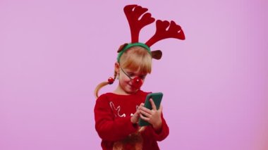 Noel geyiği boynuzları takan kız. Akıllı telefon görüntüsü. Sevinçten havalara uçuyor.