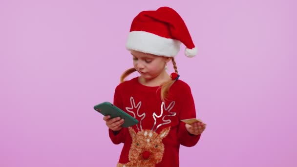 Enfant fille dans le téléphone portable sweateruse de Noël, cartes bancaires de crédit en plastique, gagner, calebrate, wow — Video