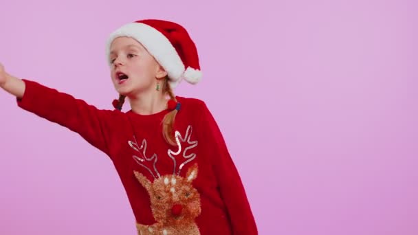 Menina em camisola de Natal enviando muitos beijos de ar olhando para a câmera, sorrindo, sentindo sua falta, amor — Vídeo de Stock