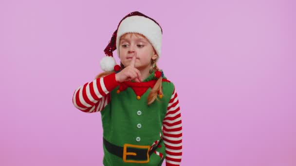 Gyermek lány karácsonyi manó jelmez nyomja mutatóujját az ajkak tesz csend gesztus jel, titkos — Stock videók