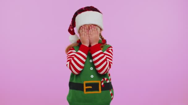 Девочка малышка Санта-рождественский эльф дурачится с закрытыми глазами и шпионит через — стоковое видео