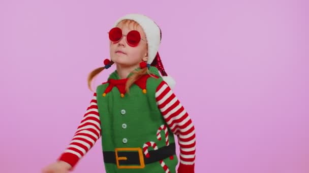 소녀 크리스마스 산타클로스 엘프 이어폰을 통해 음악을 듣고 디스코 댄스를 즐기며 즐거운 시간을 보내는 모습 — 비디오