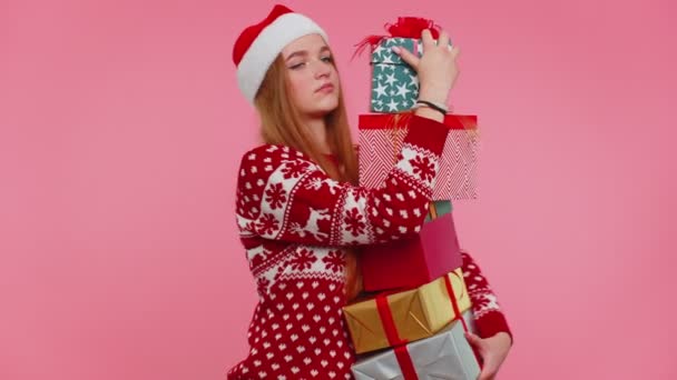 Flicka i jul röd tröja, Santa hatt leende, håller många presentförpackningar nyårspresenter shopping — Stockvideo