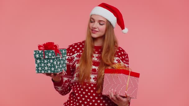 Kvinna i jul röd tröja Santa hatt, leende, håller två presentförpackningar nyår presenterar shopping — Stockvideo