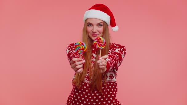 喜びの女の子で赤クリスマスセーター,帽子提示キャンディーストライプロリポップ,手を伸ばし — ストック動画