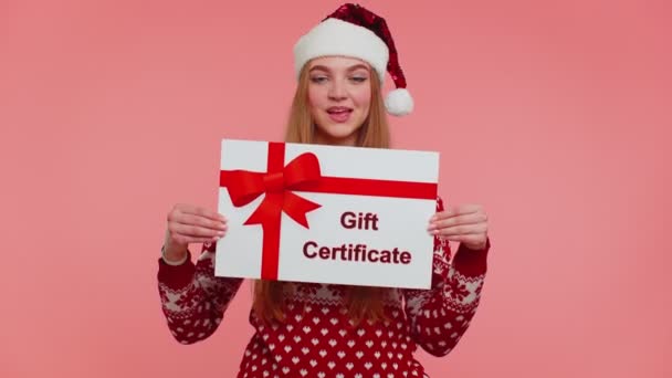 Ragazza divertente indossa maglione rosso Capodanno e cappello che presenta buono regalo buono vincitore del certificato di carta — Video Stock