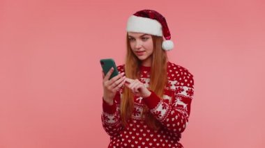 Kırmızı Noel süveteri giyen yetişkin bir kız. Akıllı telefon görüntüsü. İçten bir sevinç.