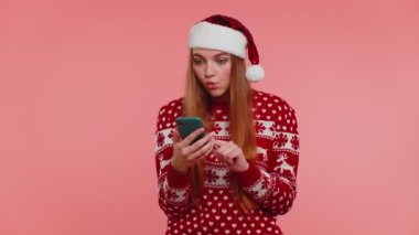 Noel süveteri giyen yetişkin bir kız. Akıllı telefon görüntüsü. İçten bir sevinç.