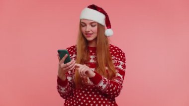 Noel süveteri giyen kadın akıllı telefon görüntüsü. İçtenlikle sevinç dolu. Başarı şansı, başparmak yukarı.