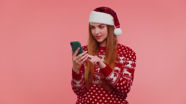Menina adulta em camisola de Natal vermelho olhando exibição smartphone sinceramente regozijando-se ganhar sucesso sorte — Vídeo de Stock