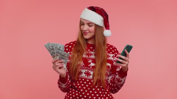 女性でクリスマスセーター見てスマートフォン誠実に勝利成功運を受け取るお金 — ストック動画