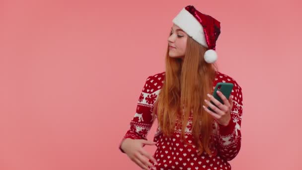 Menina em camisola de Natal Santa com telefone celular mostrando apontando lugar vazio, área de publicidade — Vídeo de Stock