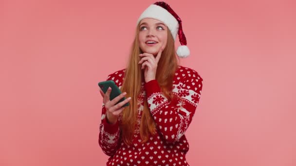 Menina em camisola de Natal Santa à procura de presentes, presente para amigos e familiares, compras on-line — Vídeo de Stock