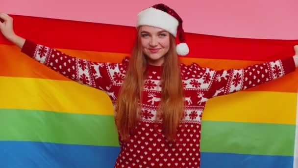 Chica en jersey de Navidad posando con bandera del arco iris celebrar desfile tolerancia matrimonios del mismo sexo — Vídeos de Stock