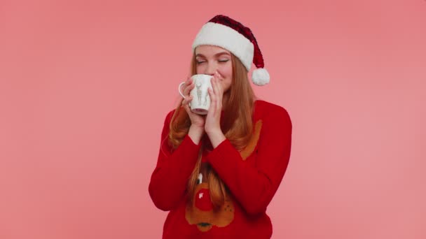 Χαρούμενο κορίτσι στα Χριστούγεννα Σάντα πουλόβερ με ζεστό ρόφημα χαμογελώντας, χαλαρώνοντας, πίνοντας καφέ ή τσάι — Αρχείο Βίντεο