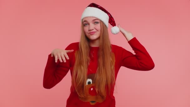 Crazy girl in Christmas Santa sweater hat demonstrating tongue out fooling around making silly faces — Stock Video