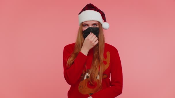 Жінка в різдвяному червоному светрі, одягнена в маску для обличчя, захищена від коронавірусу на карантині — стокове відео